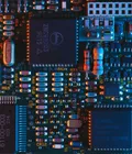 Macro photograph of a densely populated circuit board, lit in orange and teal